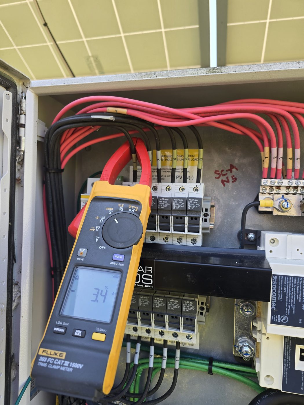 Clamp meter reading current inside a DC combiner box